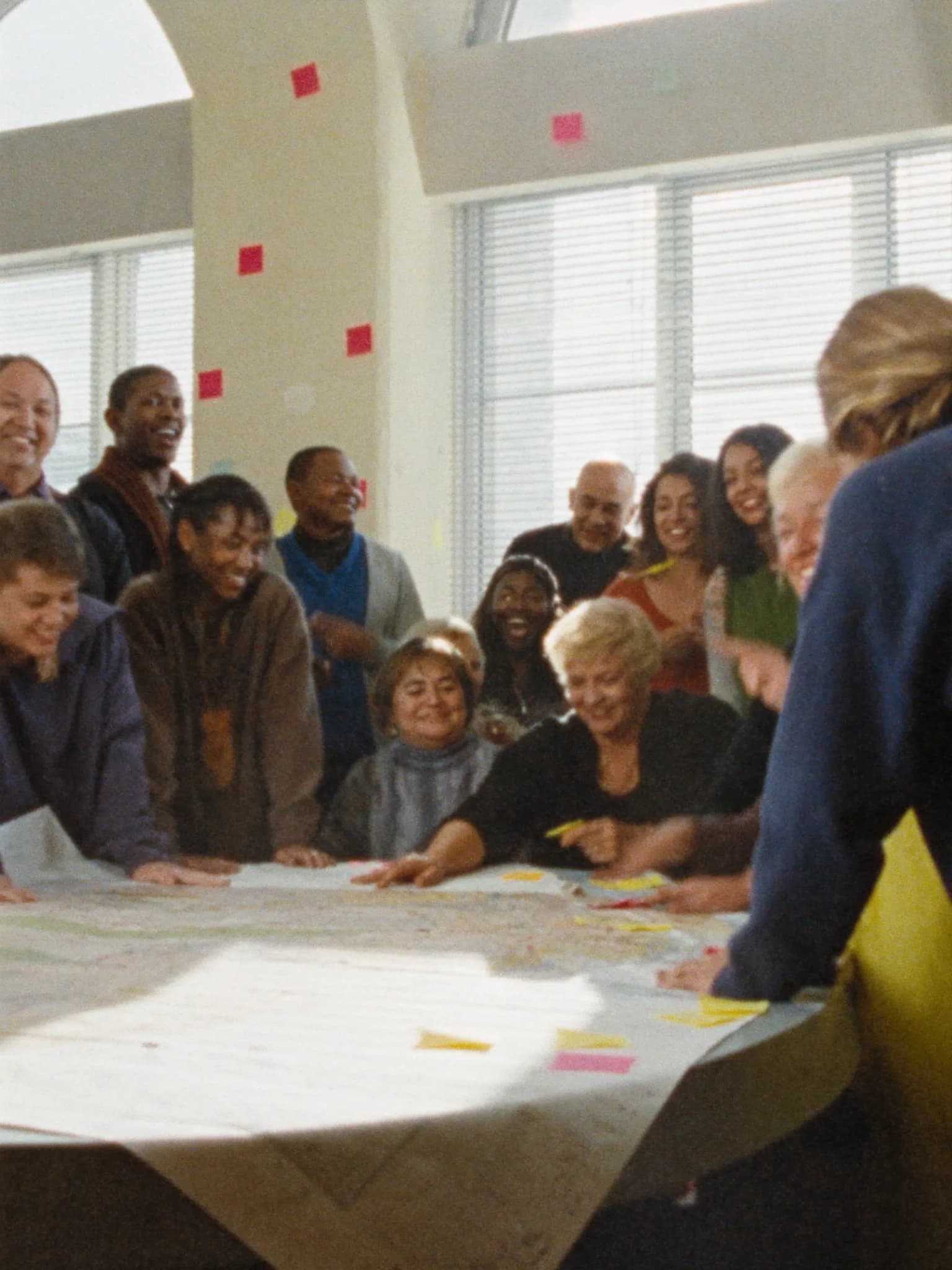 Neighbors of all ages planning together around a map in a bright community hall